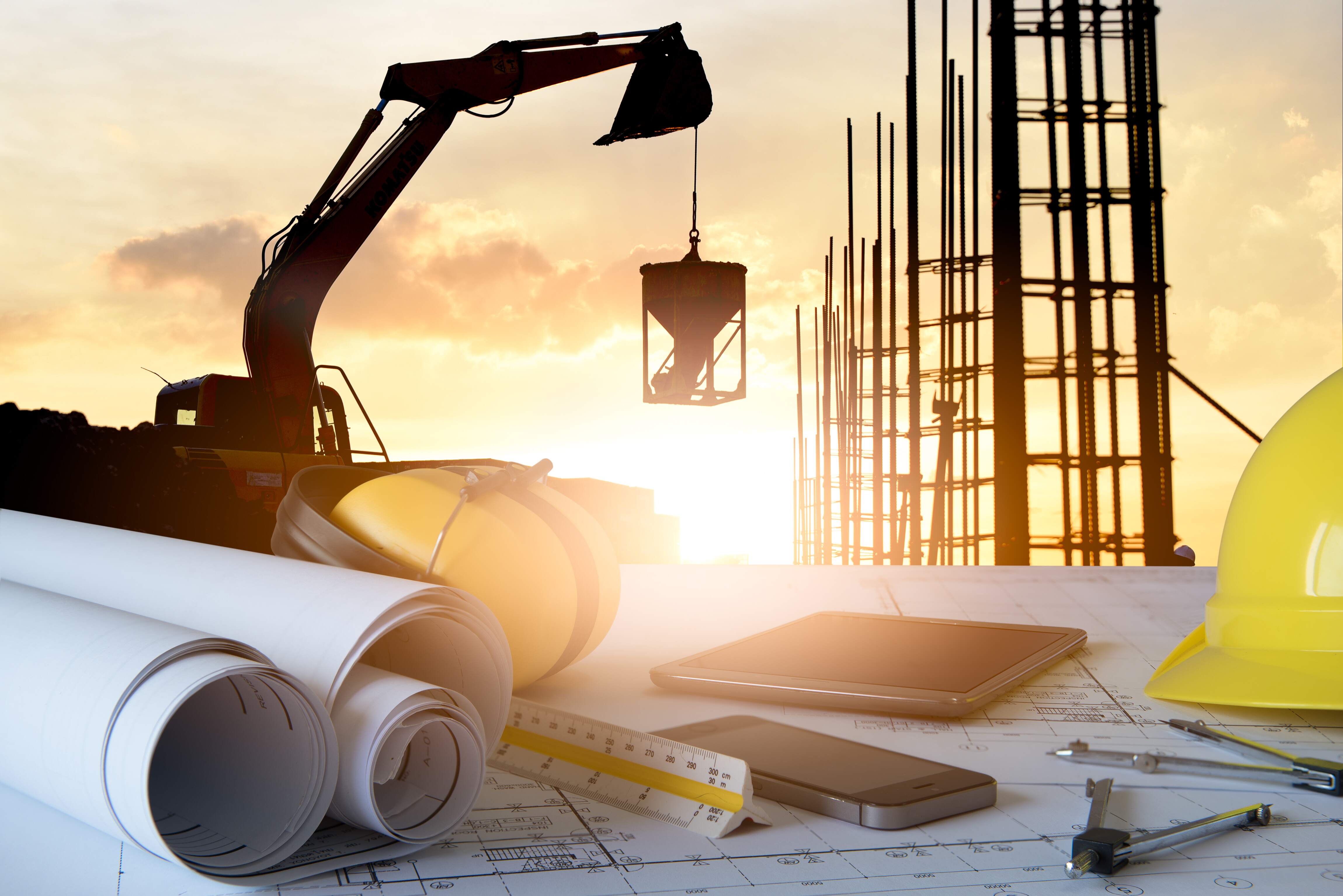 Desk of civil engineer with background silhouette of excavator activity machine
