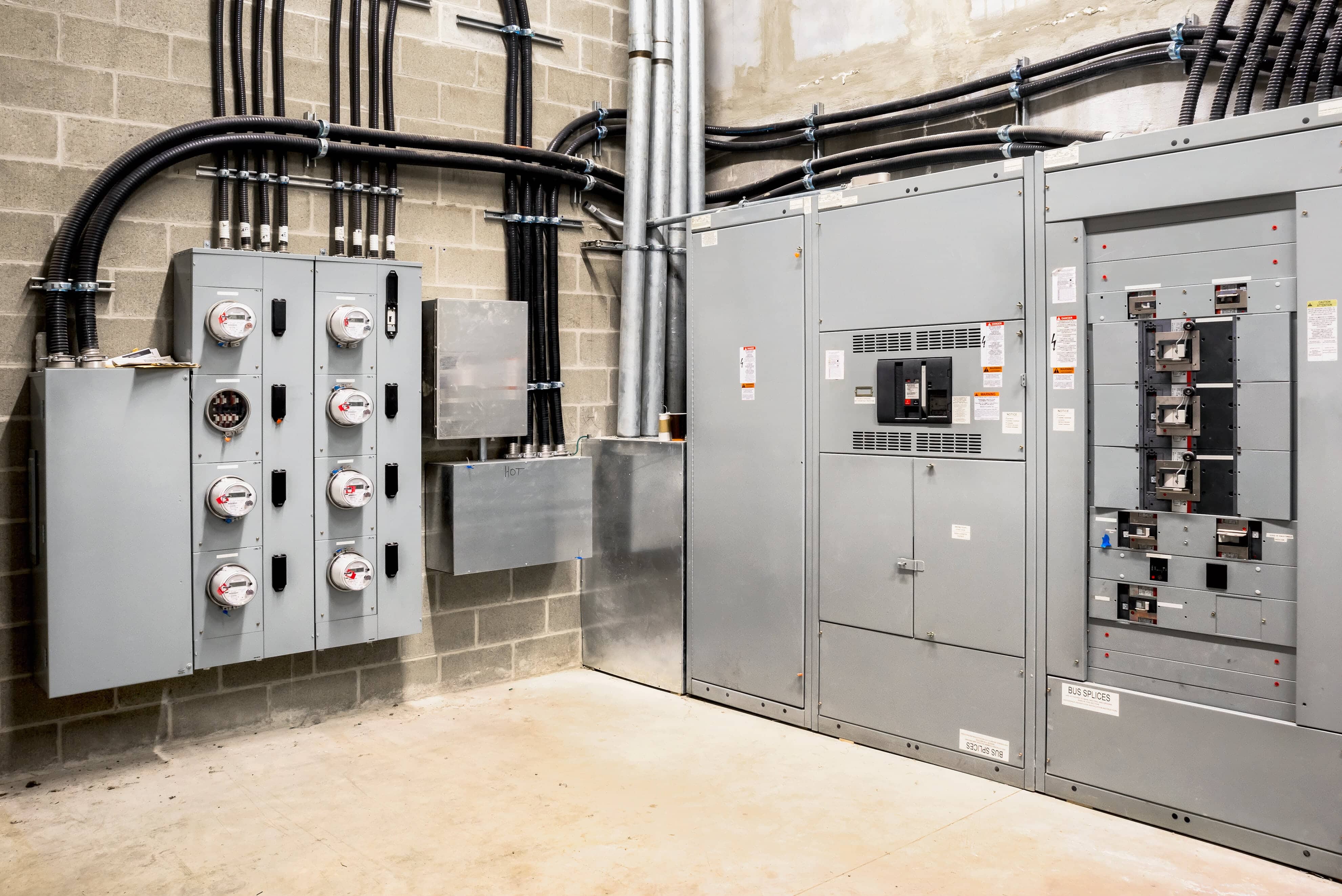 Electrical room of residential or commercial building. Multiple smart meters, main power breaker, meter stacks and cabinets